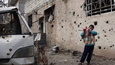 A Syrian child plays with a cardboard gun in Eastern Ghouta