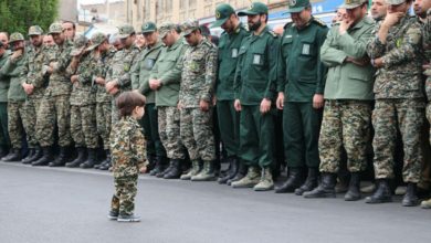 Islamic Revolutionary Guard Corps officers in tears as they look at the son of one of their colleagues, Akbar Zavar Jannati, who was killed in an airstrike in Syria