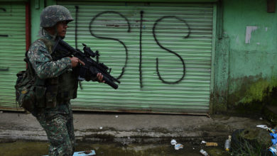 A Philippine Marine walks past graffiti during a patrol along a deserted street at the frontline in Marawi, on the southern island of Mindanao on July 22, 2017.