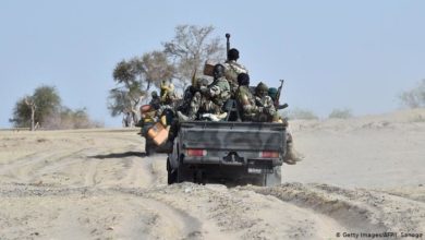 Nigerian soldiers traveling on the back of a pick-up truck.