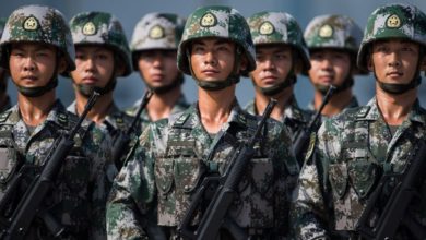Chinese soldiers look on.