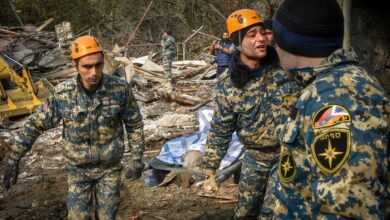 Rescuers carry the body of a woman killed by shelling during the military conflict over the Nagorno-Karabakh region.