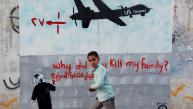 A Yemeni boy walks past a mural depicting a US drone and reading "Why did you kill my family" on December 13, 2013 in the capital Sana