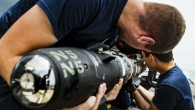 Sailors load an AGM-114 Hellfire missile onto an MH-60R Seahawk helicopter