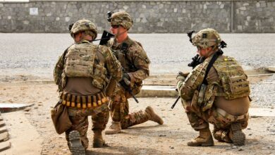 Three soldiers from the 3rd Brigade Combat Team, 101st Airborne Division (Air Assault), assigned to the Train, Advise, Assist Command - East security force, hold their positions and prepare for the landing of a UH-60 Black Hawk helicopter