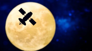 A satellite silhouette in front of a full moon