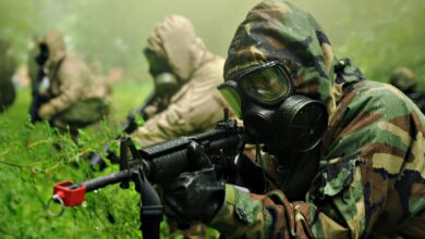 US Army soldier with the Chemical Corps points his rifle while wearing a protective gas mask.