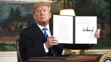 President Donald Trump signs a document reinstating sanctions against Iran