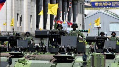 Taiwanese soldiers raise flags on military vehicles during a national day parade