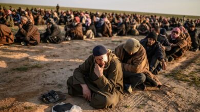 Men suspected of being Islamic State fighters wait to be searched by members