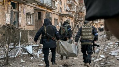 Ukrainian policemen carry a body away from a five-storey building