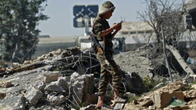 A Houthi soldier stands amidst the rubble of a building destroyed after a reported air strike by the Saudi-led coalition targeting Sanaa International Airport on 21 December 2021