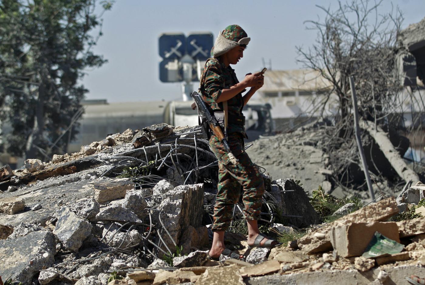 A Houthi soldier stands amidst the rubble of a building destroyed after a reported air strike by the Saudi-led coalition targeting Sanaa International Airport on 21 December 2021