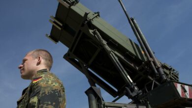 A German soldier stands to attention in front of a German Patriot missile launcher