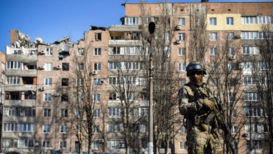 A Russian soldier outside a damaged apartment building in Donetsk
