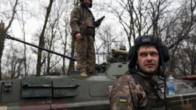 Ukrainian soldiers stand next to their armored personnel