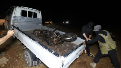 Fighters of jihadist group Hayat Tahrir al-Sham, which dominates northwestern Syria, carry away a mangled motorcyle after a US drone strike targeting a leader of a rival, Al-Qaeda-linked faction, Hurras al-Deen