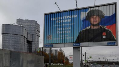 A poster displaying a Russian soldier with a slogan reading "Glory to the Heroes of Russia" is seen on a street side near the PMC Wagner Center