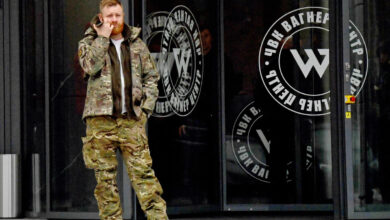 A man wearing military camouflage stands at the entrance of the PMC Wagner Centre, associated with the Wagner Group, in St. Petersburg, Russia