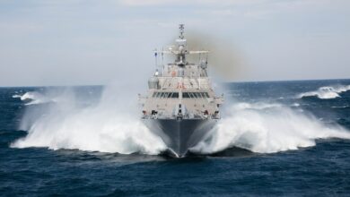 USS Milwaukee (LCS-5) sets sail in open waters. It sprays ocean water mist from its sides as it moves forward.