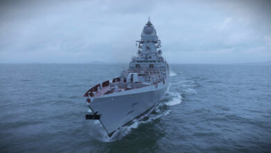 INS Imphal, India's third Visakhapatnam-class stealth guided missile destroyer, is seen sailing in calm waters. The sky is dark and overcast, completely covered by heavy grayish-white clouds that give a gloomy feel to the whole image. The ship is painted gray.
