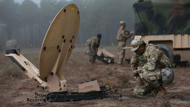 Soldier setting up a SATCOM dish on the field