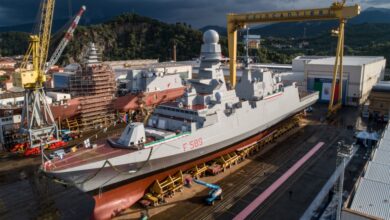 An image of the Italian Navy FREMM frigate, Emilio Bianchi, at the Riva Trigoso integrated shipyard. The ship, painted gray, is decorated with ribbons of laurels on the railings of its deck. It has "F 589" painted on its right side in red.