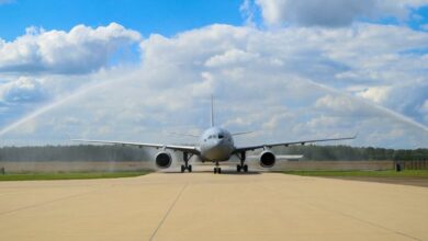 The A330 MRTT T-061 aircraft is welcomed at the MMU Main Operating Base at the traditional water arch. The plane is facing frontward.