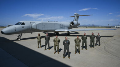 U.S. Air Force Chief Master Sgt. Andrew Small, 55th Wing command chief, Col. Mark Howard, 55th Wing commander, Lt. Gen. Thomas Hensley, 16th Air Force commander, Gen. Ken Wilsbach, commander of Air Combat Command, Chief Master Sgt. Robert Hopkins, 16th Air Force command chief, Lt. Col. Stephen Koether, 645th Aeronautical Systems Squadron Detachment 1 commander, Lt. Col. Jacob Arndt, 645 AESS Det 1 director of operations, and Maj. Mark Busby, 645 AESS Det 1 director of test, pose in front of aircraft 19-5591, ACC’s first EA-37B Compass Call delivered to Davis-Monthan AFB, Arizona, on Aug. 23, 2024. (U.S. Air Force photo by Senior Airman Paige Weldon)
