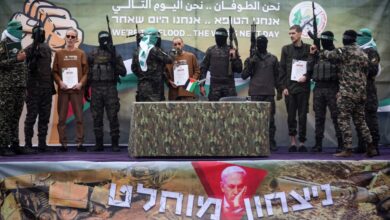 Palestinian Hamas fighters escort Israeli hostages before handing them over to a Red Cross team in Deir el-Balah, central Gaza, on February 8, 2025, as part of the fifth hostage-prisoner exchange of a fragile ceasefire.