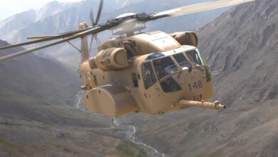 A single CH-53K helicopter flying in between mountains