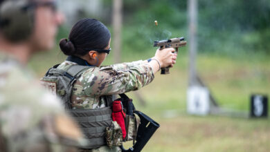 Airman Mia Marquez, 802nd Security Forces Ssquadron installation access controller, fires an M18 handgun at paper targets while U.S. Air Force Tech. Sgt. Justin Hains, 802nd Security Forces Squadron noncommissioned-officer-in-charge of training, observes the firing range while during sustainment firing training at Joint Base San Antonio-Lackland, Texas, April 9, 2024. Students participate in this training to better understand the weapons systems while also completing drills that require different firing positions to maintain proficiency and develop their firearms skills. (U.S. Air Force photo by Brian Boisvert)