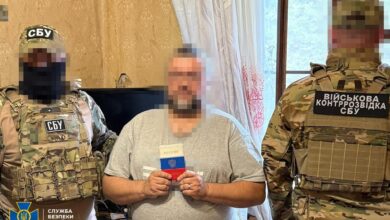 A Russian spy holding passport with Ukrainian security agency personnel. Photo: Ukrainian Security Service