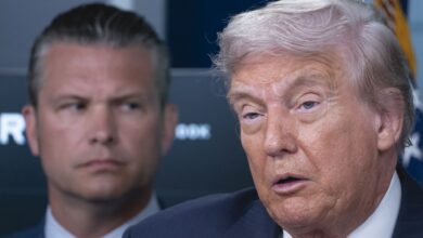 President Donald Trump speaks to reporters as Defense Secretary Pete Hegseth stands behind him