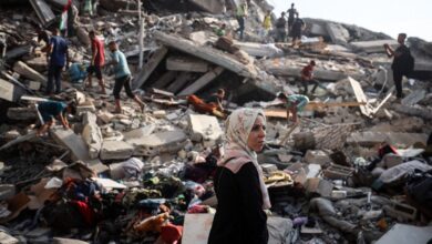 Palestinian residents walking over building rubble after an Israeli strike