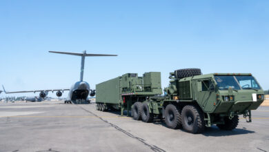 A green launcher of the Typhon missile parked behind a plane