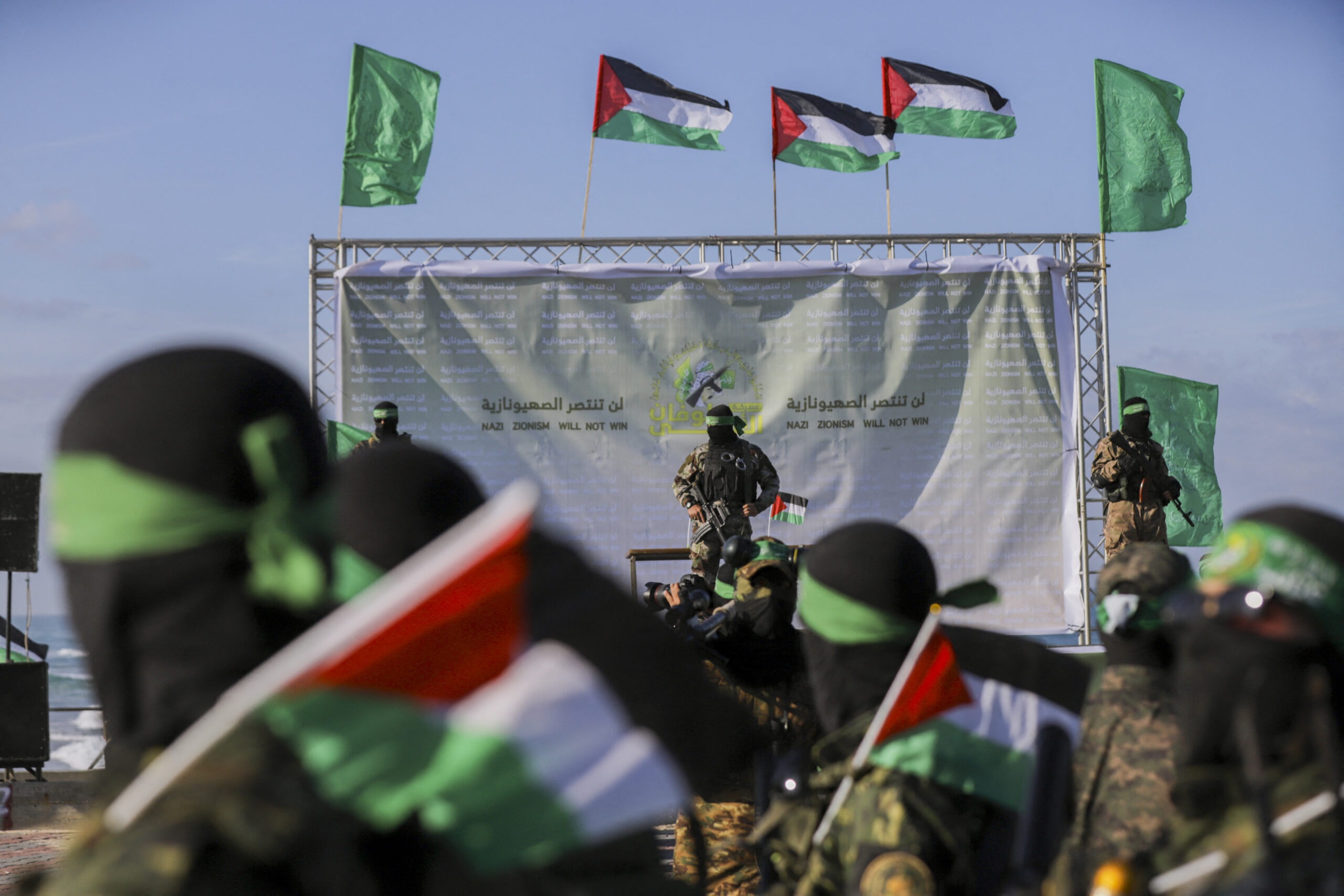 Palestinian militant group Hamas fighters secure an area before handing over an Israeli-American hostage to a Red Cross team in Gaza City on February 1, 2025, as part of the fourth hostage-prisoner exchange. Ranks of Hamas fighters formed up on Gaza's beachfront on February 1 for the handover of an Israeli-American hostage Keith Siegel in a show of force against the dramatic backdrop of breaking waves. (Photo by Saeed Jaras / Middle East Images via AFP)