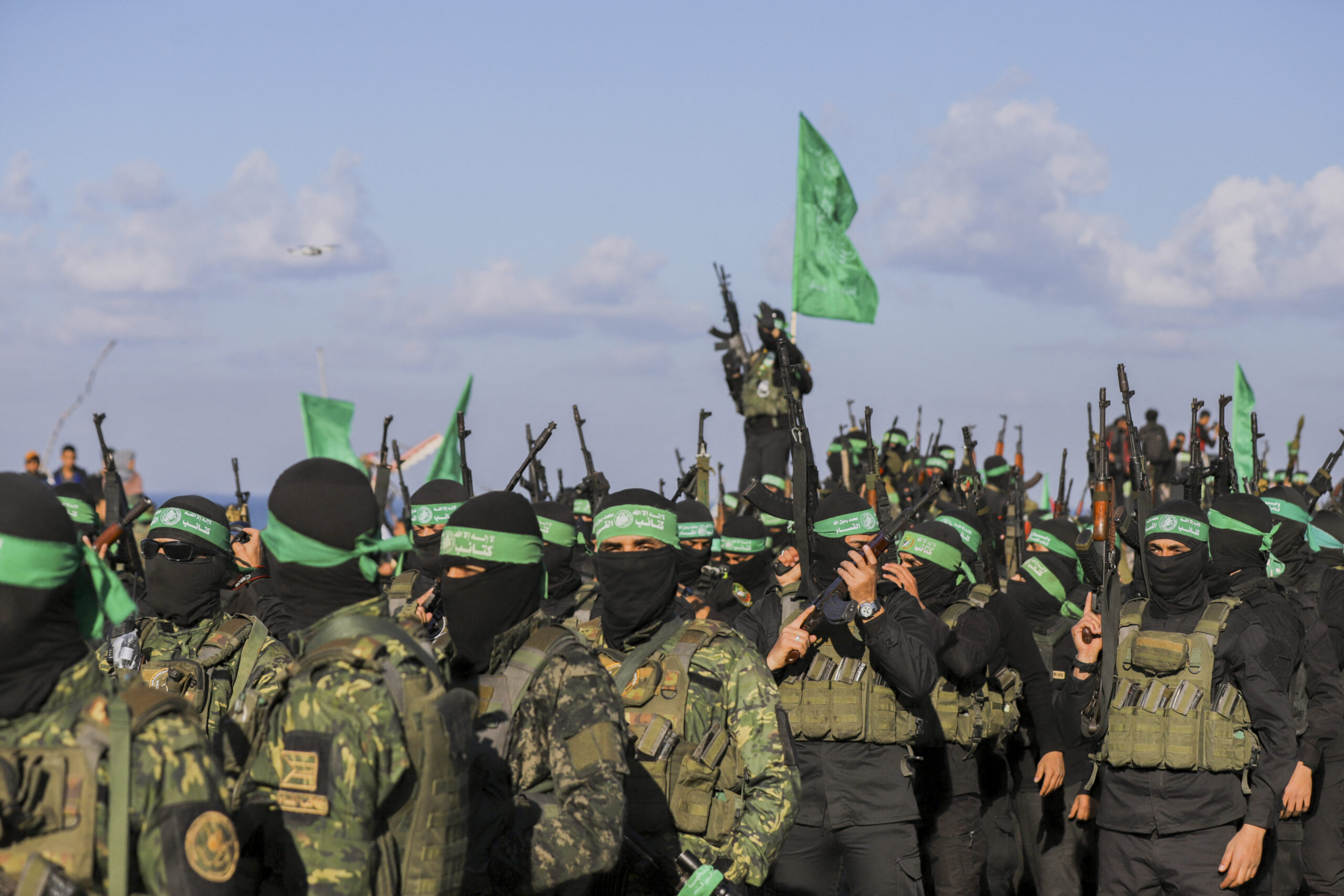 Palestinian militant group Hamas fighters secure an area before handing over an Israeli-American hostage to a Red Cross team in Gaza City on February 1, 2025, as part of the fourth hostage-prisoner exchange. Ranks of Hamas fighters formed up on Gaza's beachfront on February 1 for the handover of an Israeli-American hostage Keith Siegel in a show of force against the dramatic backdrop of breaking waves. (Photo by Saeed Jaras / Middle East Images via AFP)