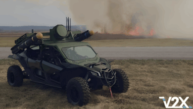 V2X's Tempest vehicle parked on a grassland with burning fires in the background