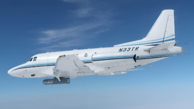 A white plane carrying the AgilePod case that contains the IRST system with a clear sky background