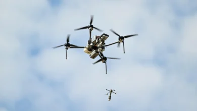 A brightly lit image of the D155 drone releasing a smaller drone while in the air with a cloudy background