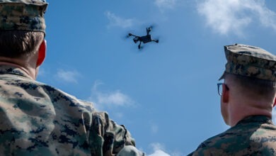 US Marines looking at a drone flying in the air with a sunny background