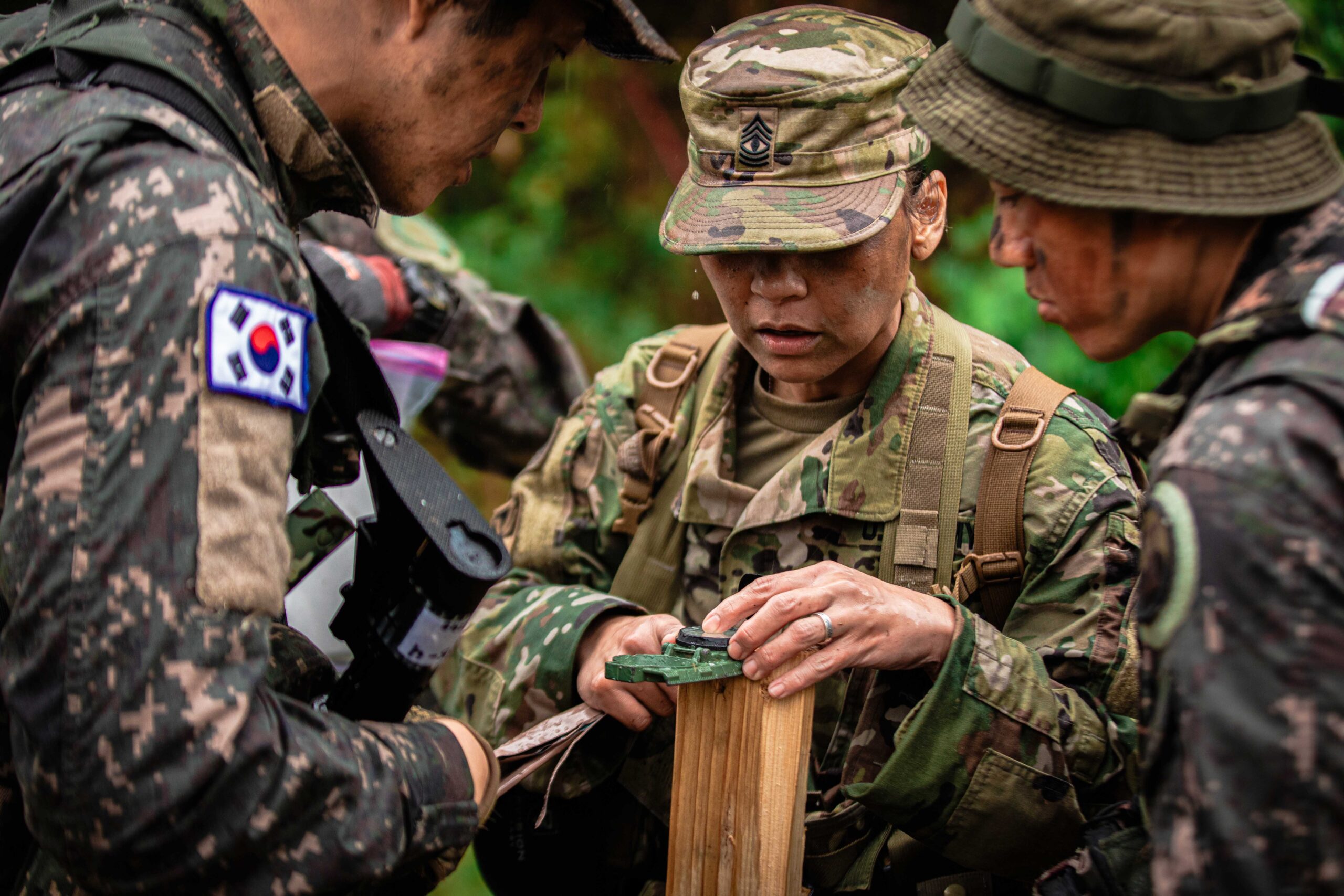 South Korean soldiers holding a wooden stick with a green forest background