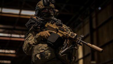 Soldier holding rifle with 3D-printed suppressor.
