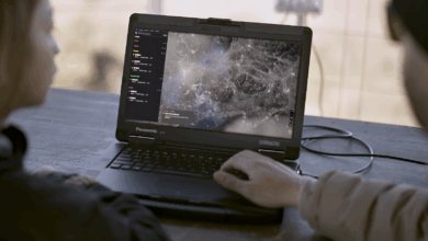 Defense operators using real-time drone surveillance software on a Panasonic Toughbook for mission control and target tracking.