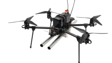 Fully assembled black quadcopter drone carrying a twin-barreled shotgun payload on a white background.