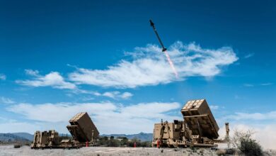 A high-speed interceptor missile launching from a mobile ground-based platform into a blue sky.