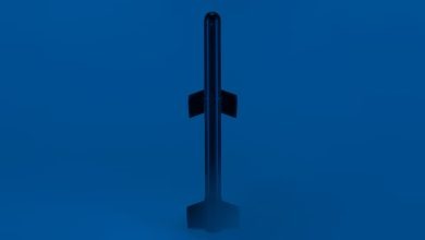 A black rocket, resembling a sleek dart with four fins, stands upright against a blue background, its base partially shrouded in mist or fog.