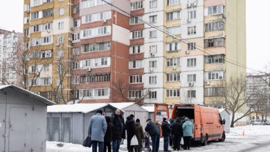 People wait in line for a mobile delivery of essential goods in the Troieshchyna district of Kyiv, Ukraine on January 30, 2026.