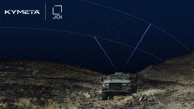Military vehicle operating at night in rugged terrain, equipped with a satellite terminal linking to overhead satellites for secure communications.